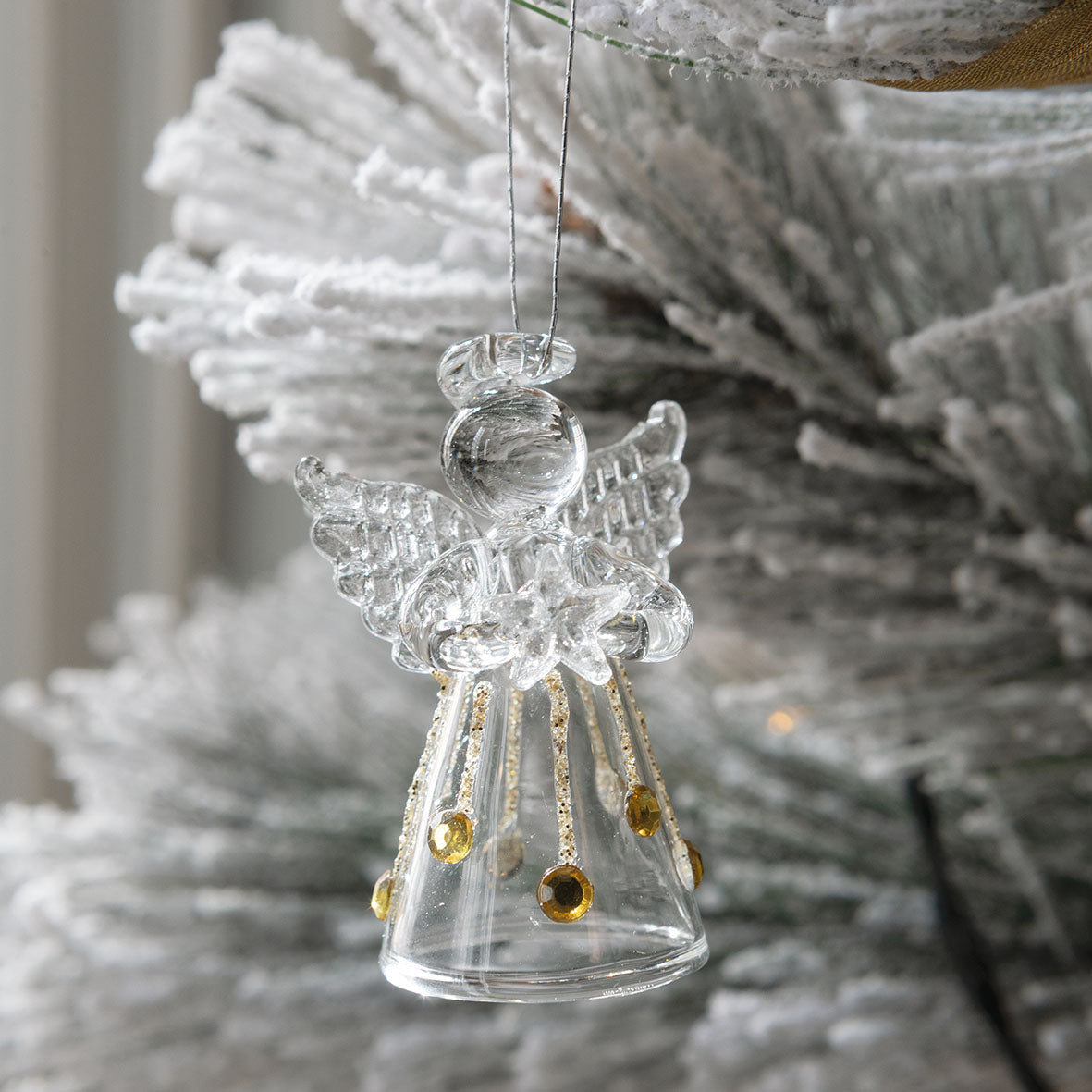 Photo mise en scène d'un mini ange suspendu sur une branche d'un sapin de Noël.