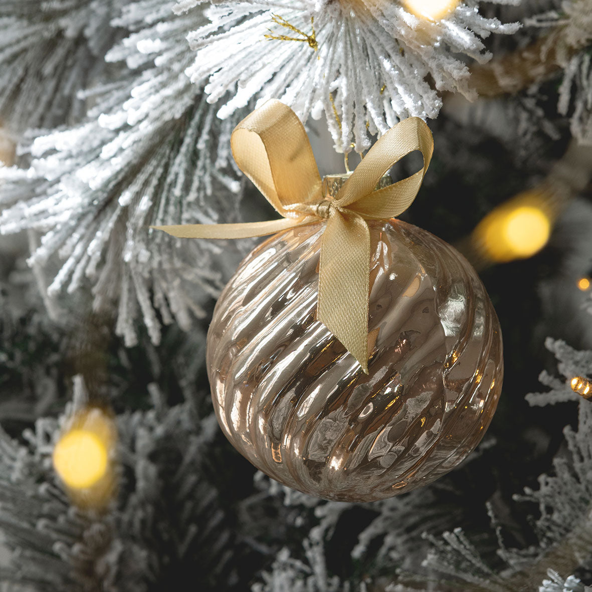 Photo mise en scène d'une boule côtelée nœud suspendu à une branche du sapin de Noël.