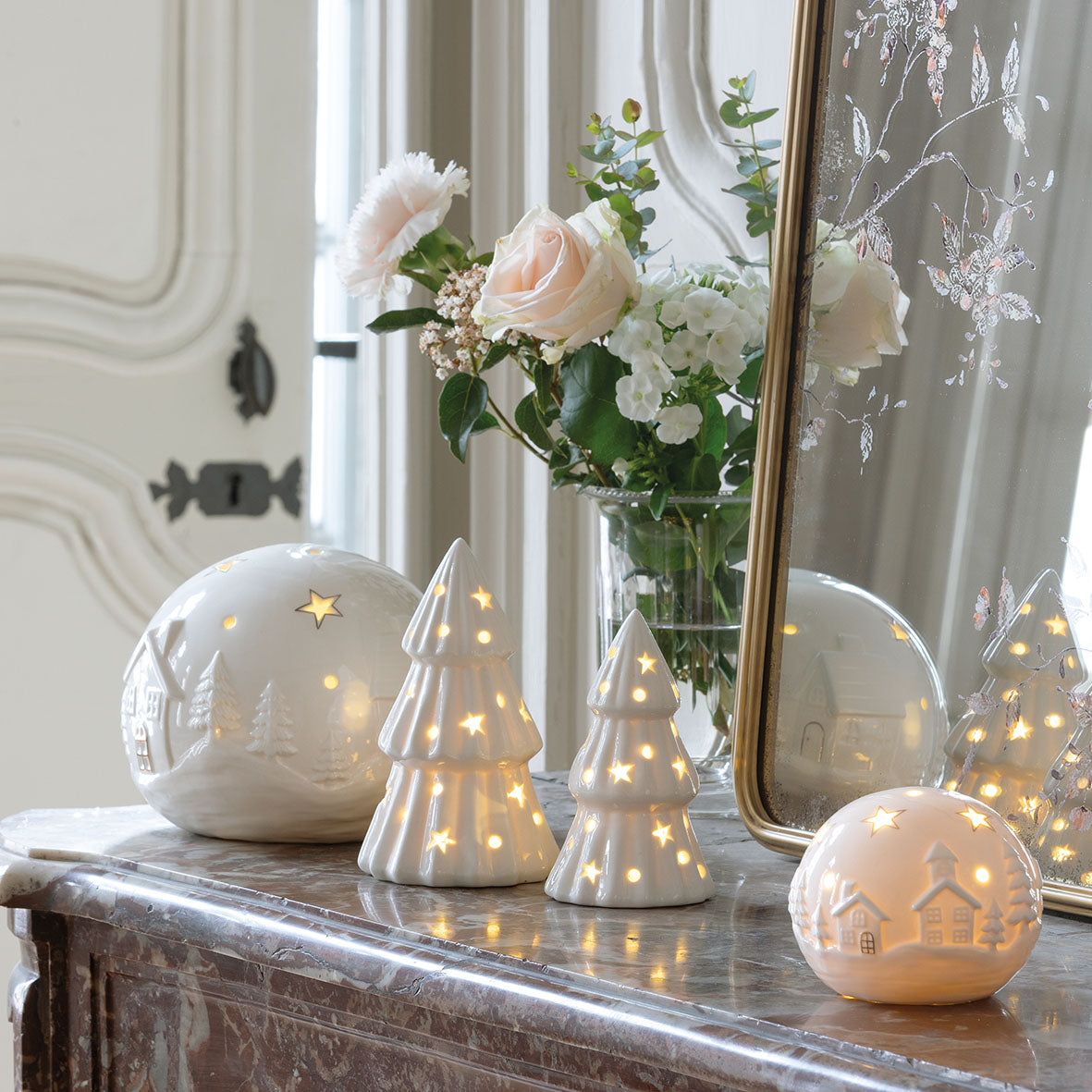 Photo mise en scène de 2 sapins décoratif de 2 tailles différentes, et 2 boules décoratives village de Noël de 2 tailles différente également