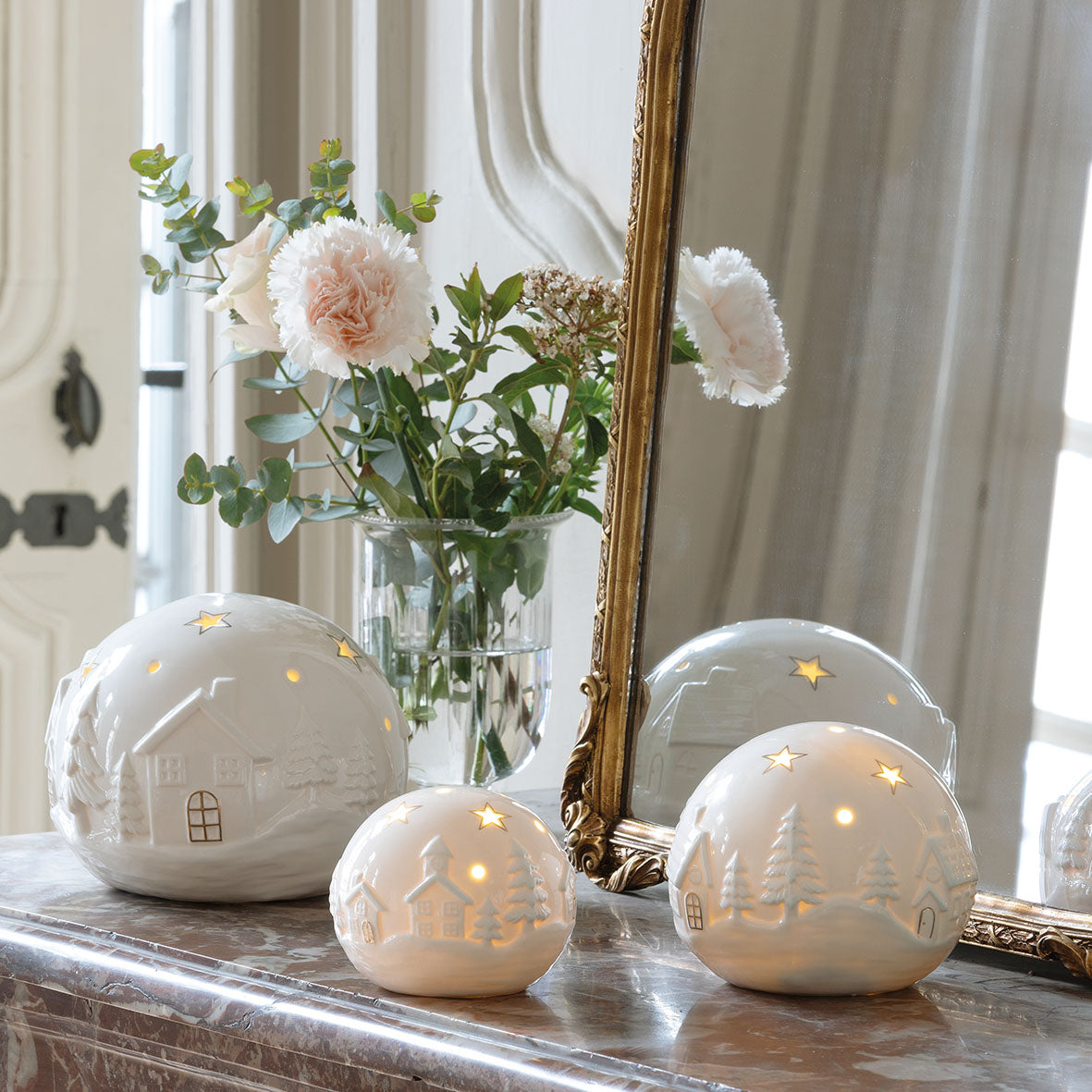 Photo mise en scène des 3 boules décoratives village de Noël en 3 tailles différentes.